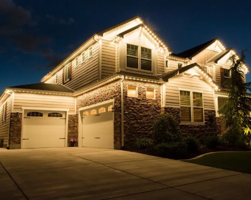 Permanent outdoor lights installed along the front roofline of a home by Osnova Construction
