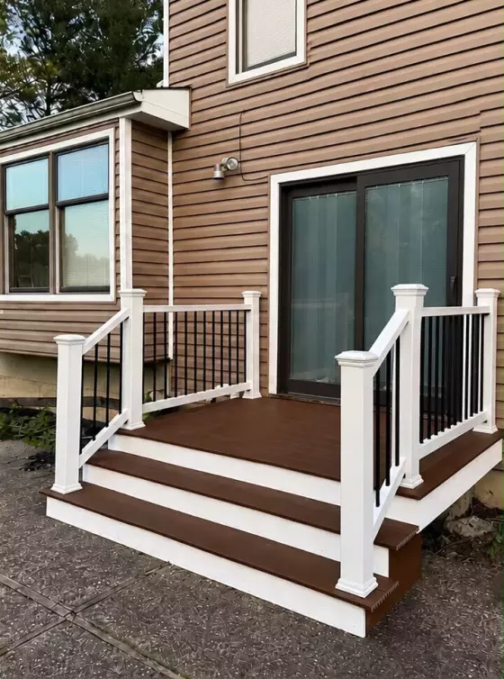 New composite deck with brown decking, white PVC railing posts, and black aluminum balusters at a West Chicago, IL home