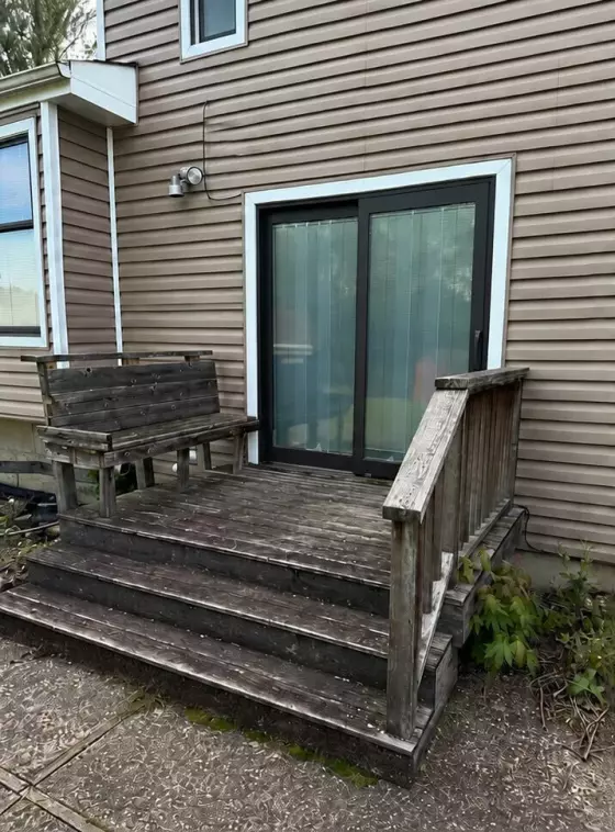 Old weathered gray wood deck with worn boards and railing before replacement at a West Chicago, IL home