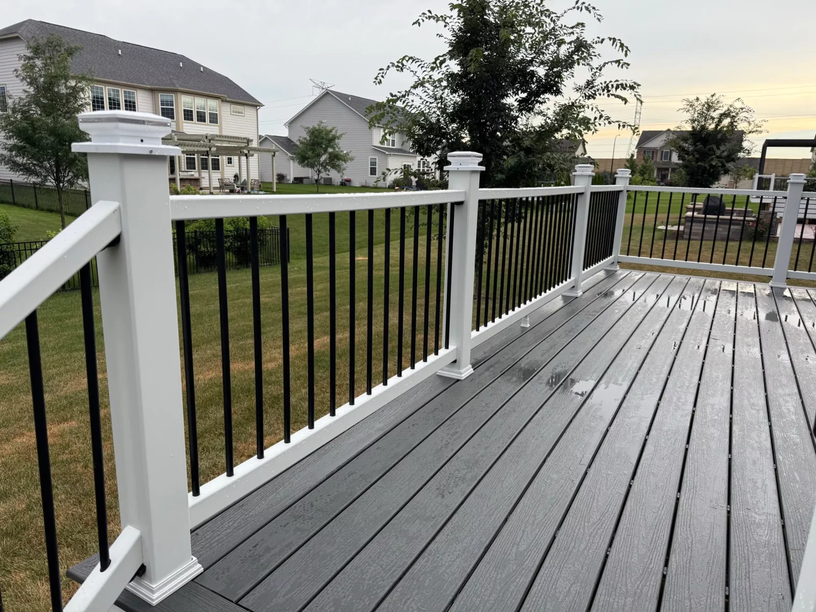 Composite deck railing with white post caps and black balusters at dusk in Naperville, IL