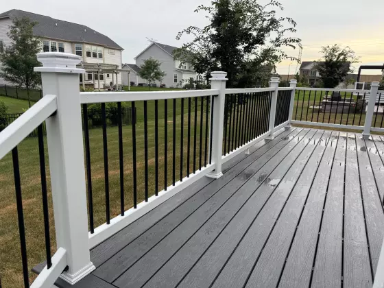 Composite deck railing with white post caps and black balusters at dusk in Naperville, IL
