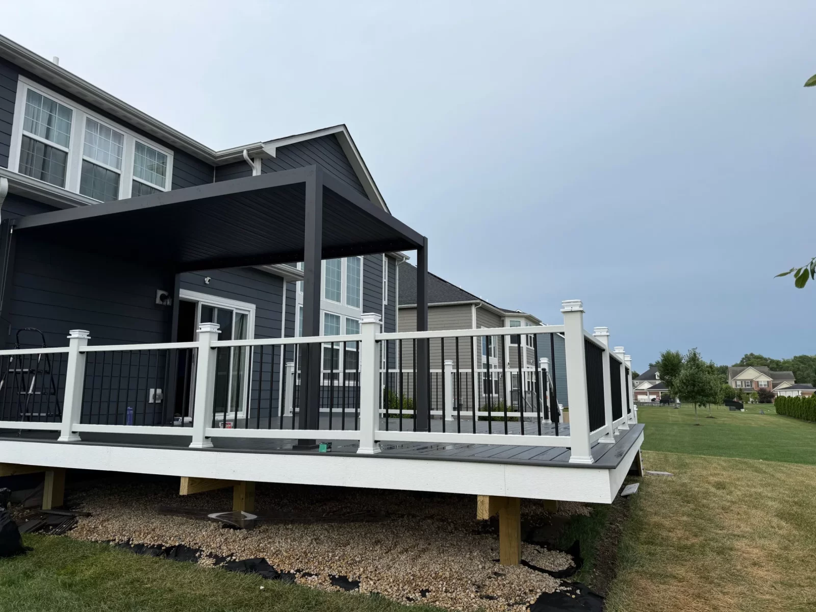 Custom composite deck with white railing and black balusters along a dark blue home in Naperville, IL