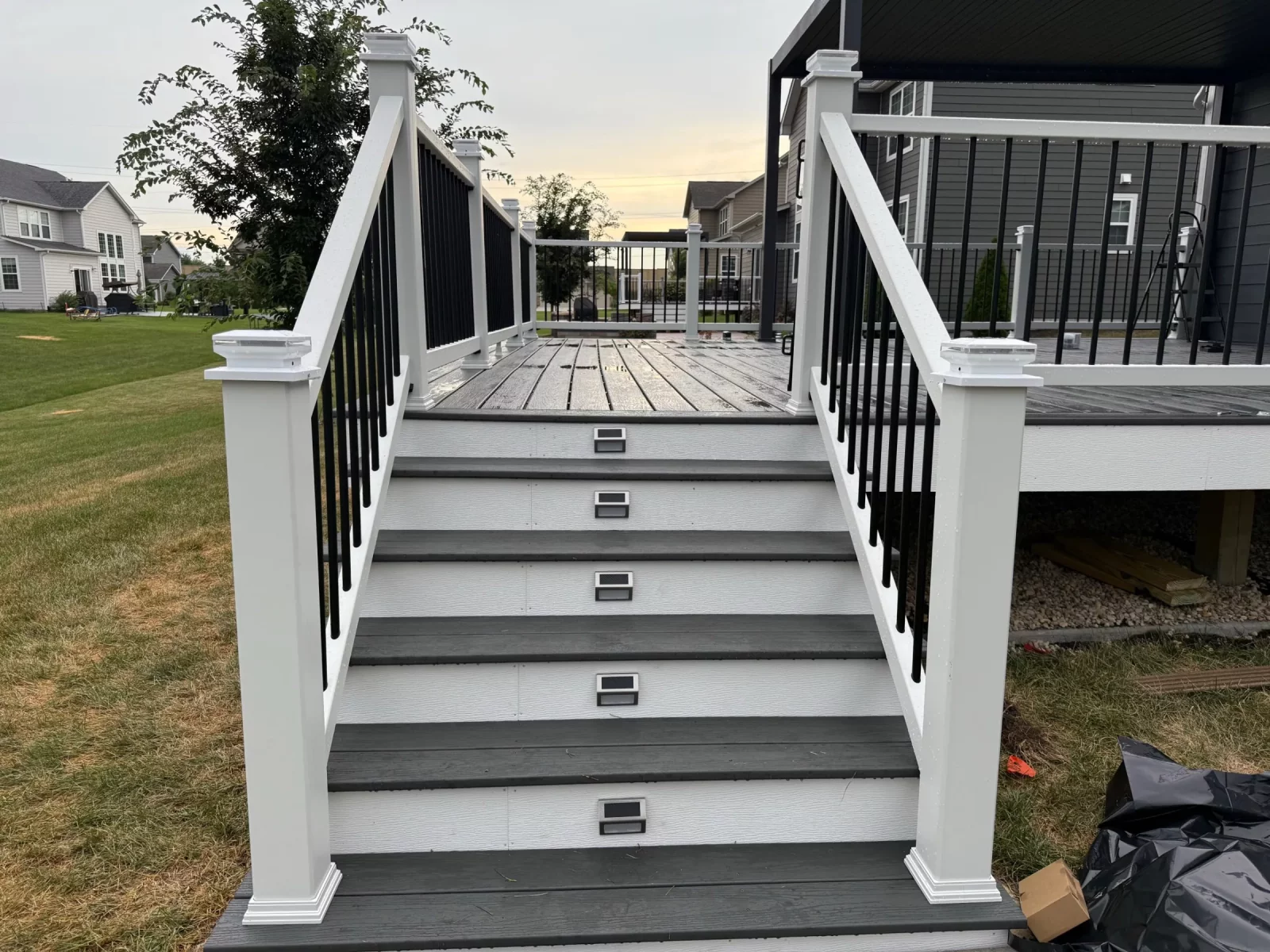 Composite deck staircase with gray steps and solar step lights leading up to a railed deck in Naperville, IL