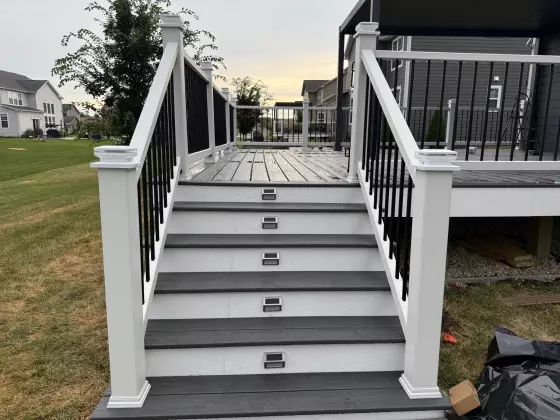 Composite deck staircase with gray steps and solar step lights leading up to a railed deck in Naperville, IL
