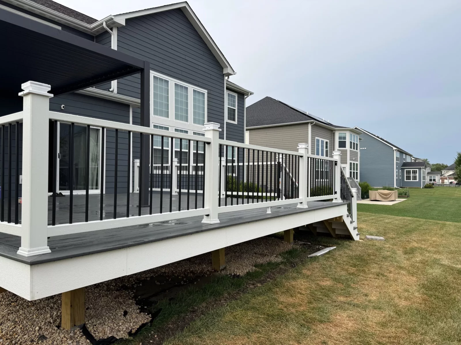 Composite deck running along the back of a dark blue home with white-and-black railing in Naperville, IL