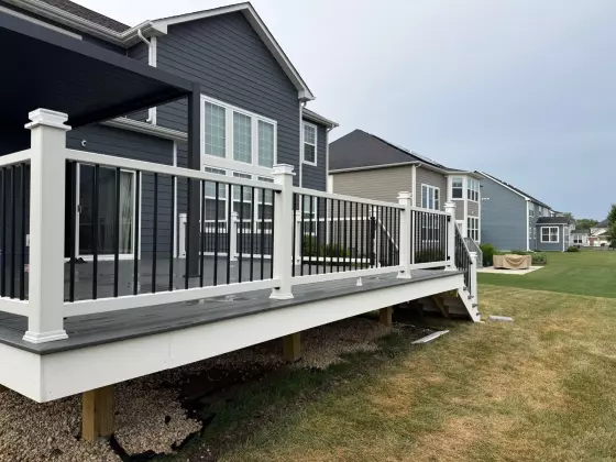 Composite deck running along the back of a dark blue home with white-and-black railing in Naperville, IL