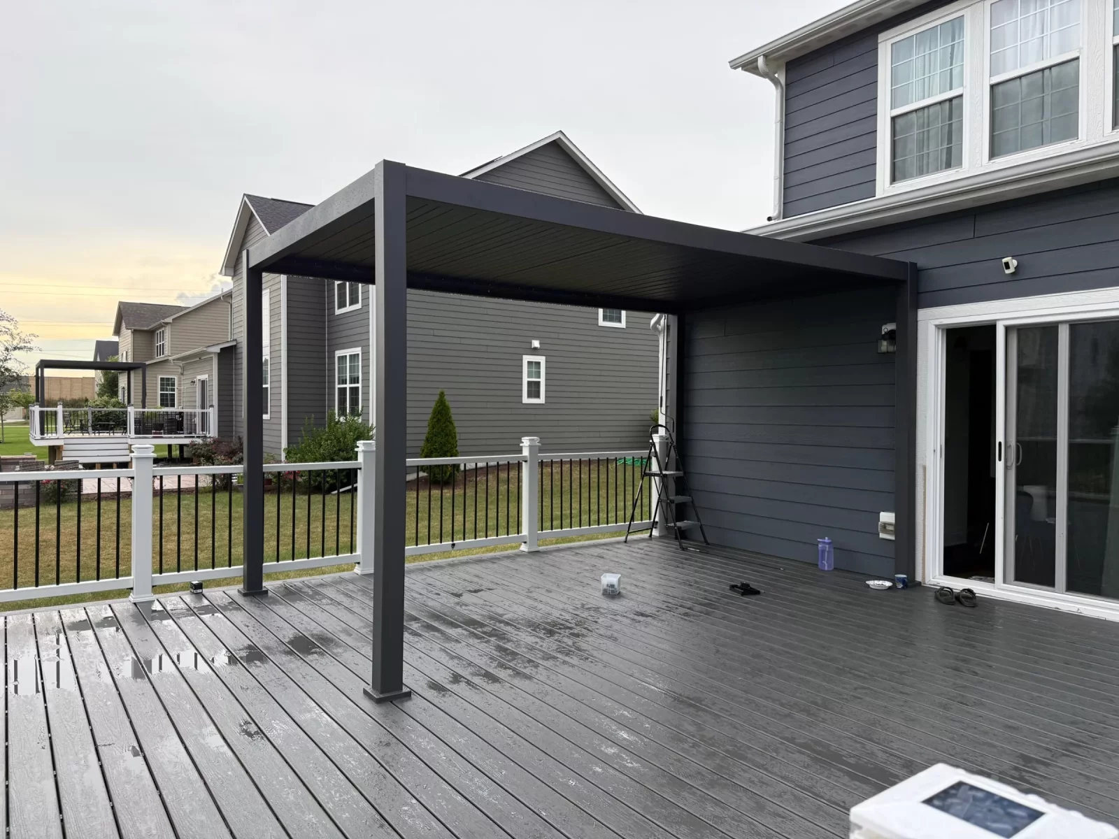 Modern black aluminum pergola over a composite deck beside sliding patio doors in Naperville, IL
