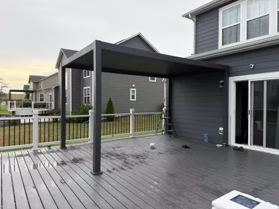 Modern black aluminum pergola over a composite deck beside sliding patio doors in Naperville, IL
