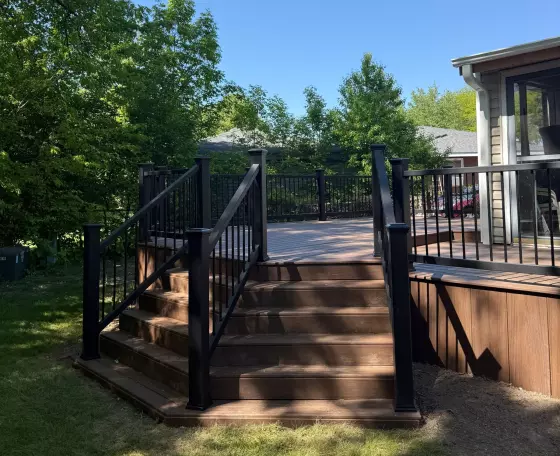 Remodeled deck with composite decking, black composite railing, and refreshed stairs in Aurora, IL
