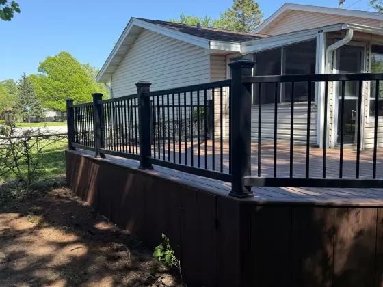 Refreshed composite deck with black railing and matching skirting beside the home in Aurora, IL