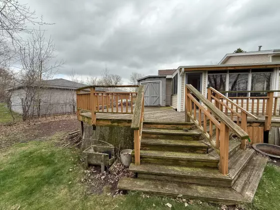Old weathered wood deck with aged railing and worn stairs under an overcast sky before remodeling in Aurora, IL