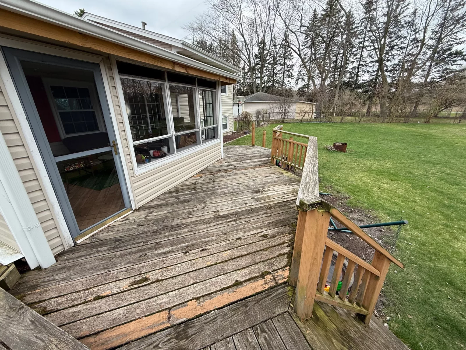 Old weathered wood deck with gray, rotting boards and aged wood railing before remodeling in Aurora, IL